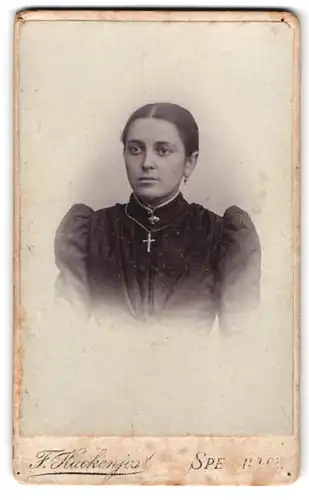 Fotografie F. Hackenjost, Speier a. Rh., am Museum, Portrait junge Frau im schwarzen Kleid mit Puffärmel und Kreuz Kette