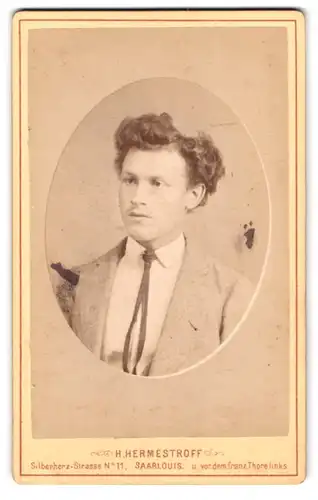 Fotografie H. Hermestroff, Saarlouis, Silberherz-Str. 11, Portrait junger Mann im Anzug mit offener Fliege und Locken