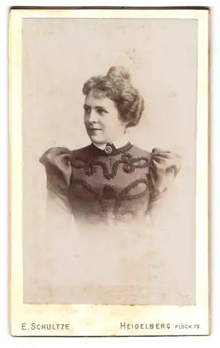 Fotografie E. Schultze, Heidelberg, Plöck 79, Portrait bildschöne junge Frau mit Dutt in besticktem Kleid