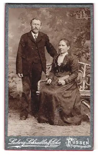 Fotografie Ludwig Schradler & Sohn, Füssen, Augsburgerstr. 276, betagtes Paar wohl gekleidet vor Studiokulisse