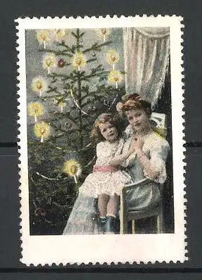 Reklamemarke Mutter und Tochter vor einem beleuchteten Weihnachtsbaum sitzend