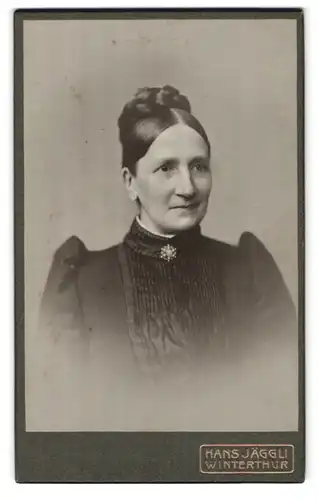 Fotografie Hans Jäggu, Winterthur, Rudolfstr., Portrait elegant gekleidete Dame mit Flechtdutt