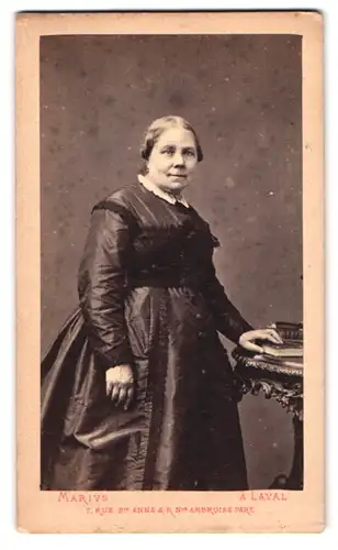 Fotografie Marvis, Laval, Rue St. Anne 7, Portrait rundliche Dame im seidenen Kleid steht am Tisch