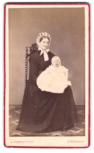 Fotografie A. Rombaut, St. Nikolaas, Nieuwstraat 60, Portrait ältere Frau im Kleid mit Haube und Kleinkind auf dem Schoss