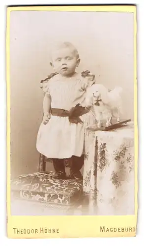 Fotografie Theodor Höhne, Magdeburg, Ullrichstr. 18, Portrait Kleinkind im weissen Kleid mit Spielzeughund auf Rollen