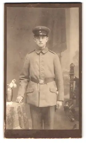Fotografie Fotograf und Ort unbekannt, Portrait junger Soldat in Feldgrau Uniform posiert im Atelier