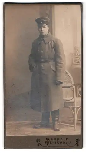 Fotografie W. Arnold, Freyburg a. U., Schützenstr. 7, Portrait junger Soldat in Feldgrau Uniform mit Mantel