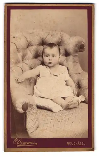 Fotografie Atelier Olsommer, Neuchatel, Baby im weissen Kleidchen auf Sessel sitzend