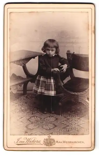 Fotografie J. von Wichera, Mähr. Weisskirchen, hübsches kleines Mädchen an Sessel festhaltend