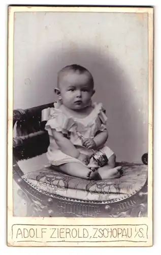 Fotografie Adolf Zierold, Zschopau, Bürhl 296, Portrait süsses Kleinkind im weissen Hemd mit Rassel