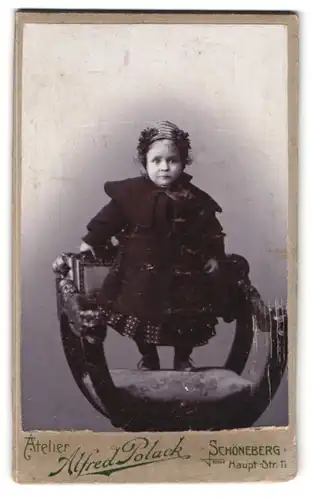 Fotografie Alfred Polack, Berlin-Schöneberg, Hauptstr. 11, Mädchen im schwarzen Mantel auf Sessel stehend