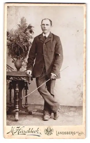 Fotografie M. Hirschbeck, Landsberg a. Lech, Portrait modisch gekleideter Herr mit Stock