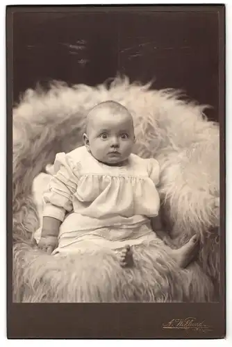 Fotografie A. Wiklund, Falun, Portrait Kleinkind im weissen Kleid auf einem Fell sitzend