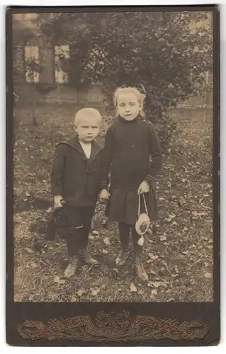 Fotografie Fotograf und Ort unbekannt, Portrait Geschwister in dunkler Kleidung mit Handtasche und Teddybär