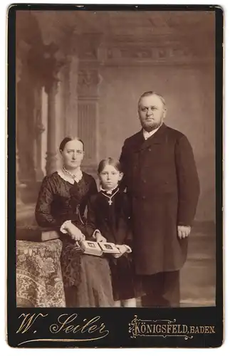 Fotografie W. Seiler, Königsfeld, Familie blättert im Fotoalbum