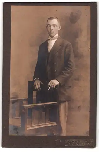 Fotografie Otto Heftl, Freiberg i. S., Portrait junger Mann im Anzug mit Schlips und Segelohren, Zigarette