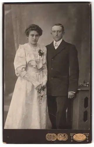 Fotografie Max Seifert, Freiberg i. S., Poststr. 11, Portrait junges Paar im Kleid und Anzug mit Locken