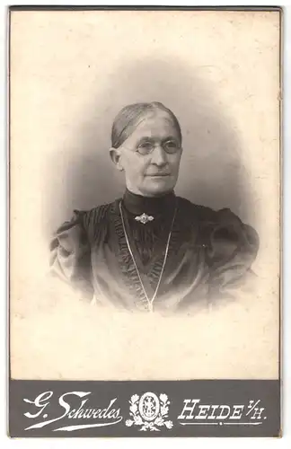 Fotografie G. Schwedes, Heide i. H., Bahnhofsgang 5, Portrait alte Frau im Biedermeierkleid mit Halskette und Brille