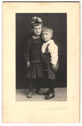 Fotografie Fotograf und Ort unbekannt, Portrait kleine Kinder in Latzhose und Kleid mit Haarschleife
