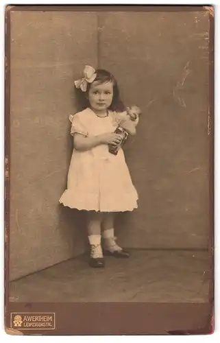 Fotografie A. Wertheim, Berlin, Leipzigerstr., Portrait kleine Mädchen im weissen Kleid mit Puppe in die Ecke stehend