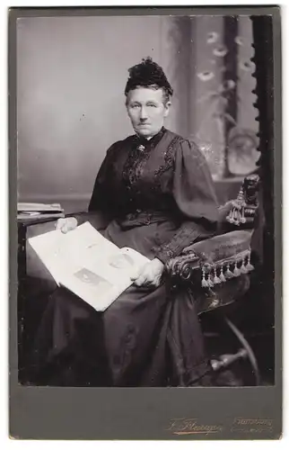 Fotografie F. Flarup, Flensburg, Grossestr. 75, Ältere Dame in Kleid trägt Haarschmuck und sitzt lesend auf Stuhl