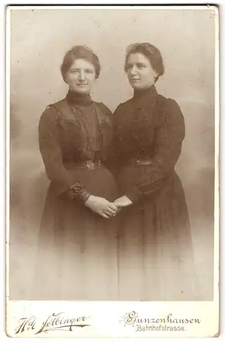 Fotografie H. Fettinger, Gunzenhausen, Bahnhofstr., Zwei Damen in dunklen verzierten Kleidern halten Hände