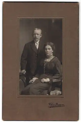 Fotografie Chr. Jessen, Delmenhorst, Sitzende Dame mit Halskette und stehender Mann mit weisser Krawatte
