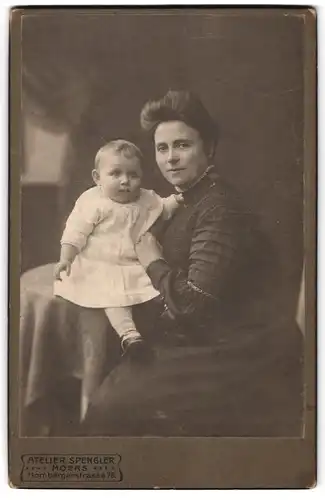 Fotografie Atelier Spengler, Moers, Hombergerstr. 76, Dame mit hochgesteckten Haaren hält Kleinkind in weissem Kleid