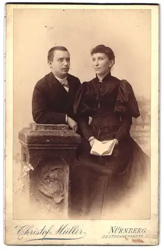 Fotografie Christof Müller, Nürnberg, Deutschherrnstr. 3, Junger Herr mit Fliege und Dame mit Buch stehen neben Säule