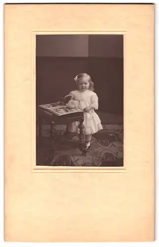 Fotografie unbekannter Fotograf und Ort, Kleines Mädchen in weissem Kleidchen spielt mit Stofftieren