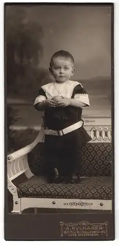 Fotografie A. Kulhanek, Berlin, Müllerstr. 137, Kleiner Junge steht auf Bank und hält einen Ball in den Händen