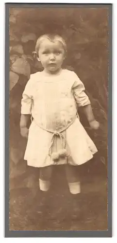 Fotografie Fotograf und Ort unbekannt, Kleinkind trägt weisses Kleid mit Bommeln