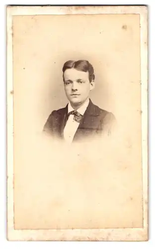 Fotografie W. Baker, Stockton-on-Tees, Portrait junger Knabe im Anzug mit Fliege und Mittelscheitel
