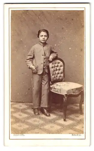 Fotografie Hertel, Mainz, Ballplatz 4, Portrait junger Knabe im Anzug lehnt an einem Stuhl