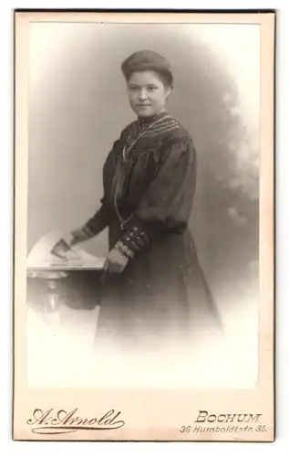 Fotografie A. Arnold, Bochum, Humboldstr. 38, Portrait Dame im Biedermeierkleid mit Halskette blättert im Buch