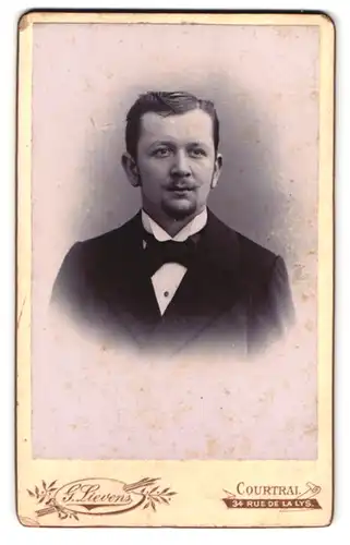Fotografie G. Lievens, Courtrai, Rue de la Lys 34, Portrait junger Mann im Anzug mit Fliege und Moustache