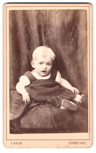 Fotografie C. F. Halm, Konstanz, Rosgartenstr. 20, Baby im dunklen Kleid mit blonden Haaren