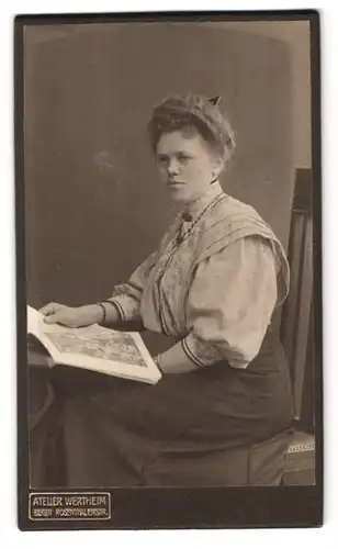 Fotografie Atellier Wertheim, Berlin, Rosenthalerstr., Frau in grauer Bluse mit einer Zeitung am Sitzen