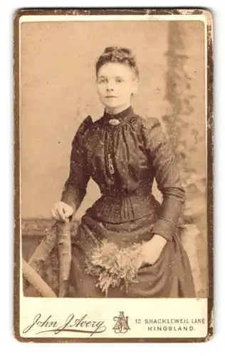 Fotografie John J. Avery, London, 12 Shacklewell Lane, Junge Frau im dunklen Kleid mit Flieder in der Hand