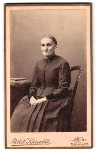 Fotografie Robert Krewaldt, Bonn, Kaiserplatz 15, Portrait ältere Dame im Biedermeierkleid sitzend auf einem Stuhl