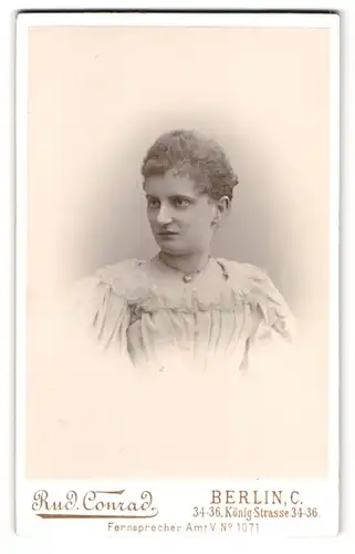 Fotografie Rud. Conrad, Berlin, König-Str. 34-36, Portrait Dame im weissen Spitzenkleid mit Locken