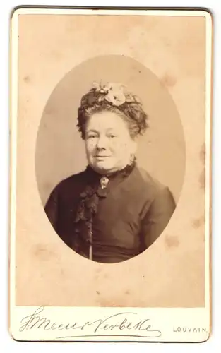 Fotografie F. Meeus-Verbeke, Louvain, Rue de la Station 24, Portrait ältere Dame im Kleid mit Blumenhut