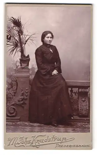 Fotografie M. Johs. Knudstrup, Frederikshavn, Portrait Dame im schwarzen Kleid mit grossen Kreuz um den Hals