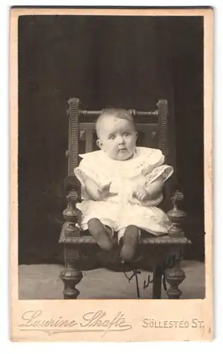 Fotografie Laurine Skafte, Söllestedt St., Portrait Kleinkind im weissen Kleid sitzt auf einem Stuhl