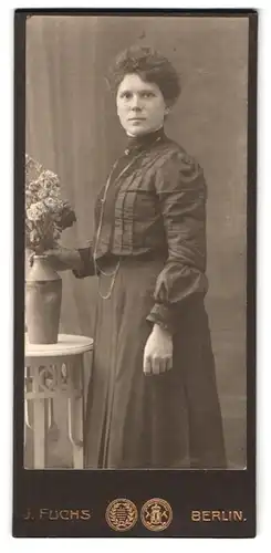 Fotografie J. Fuchs, Berlin, Friedrichstr. 108, Frau im dunklen Kleid mit Blumenstrauss