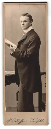 Fotografie P. Schiffer, Krefeld, Neue Linnerstr. 74, Portrait junger Mann im Anzug mit Buch in der Hand
