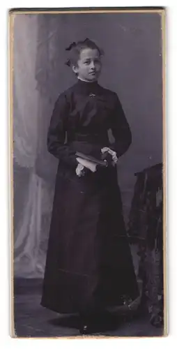 Fotografie Fotograf und Ort unbekannt, Portrait Mädchen im schwarzen Kleid mit Bibel in der Hand, Kommunion