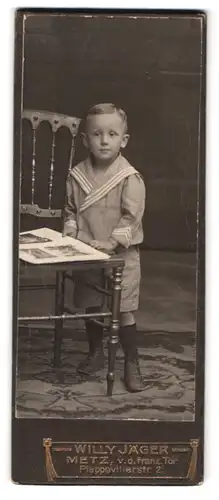 Fotografie Willy Jäger, Metz, Plappevillerstr. 2, Portrait kleiner Junge im Matrosenanzug blättert im Fotoalbum