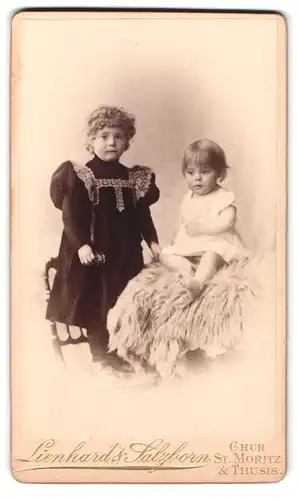 Fotografie Lienhard & Salzborn, Chur, neben der Post, Portrait zwei Mädchen in Kleidern mit Locken auf einem Fell