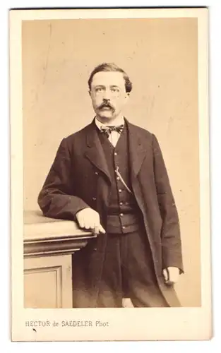 Fotografie Hector de Saedeler, Bruxelles, Chaussee de Haecht 38, Portrait Mann im Anzug samt Fliege, Walrossbart